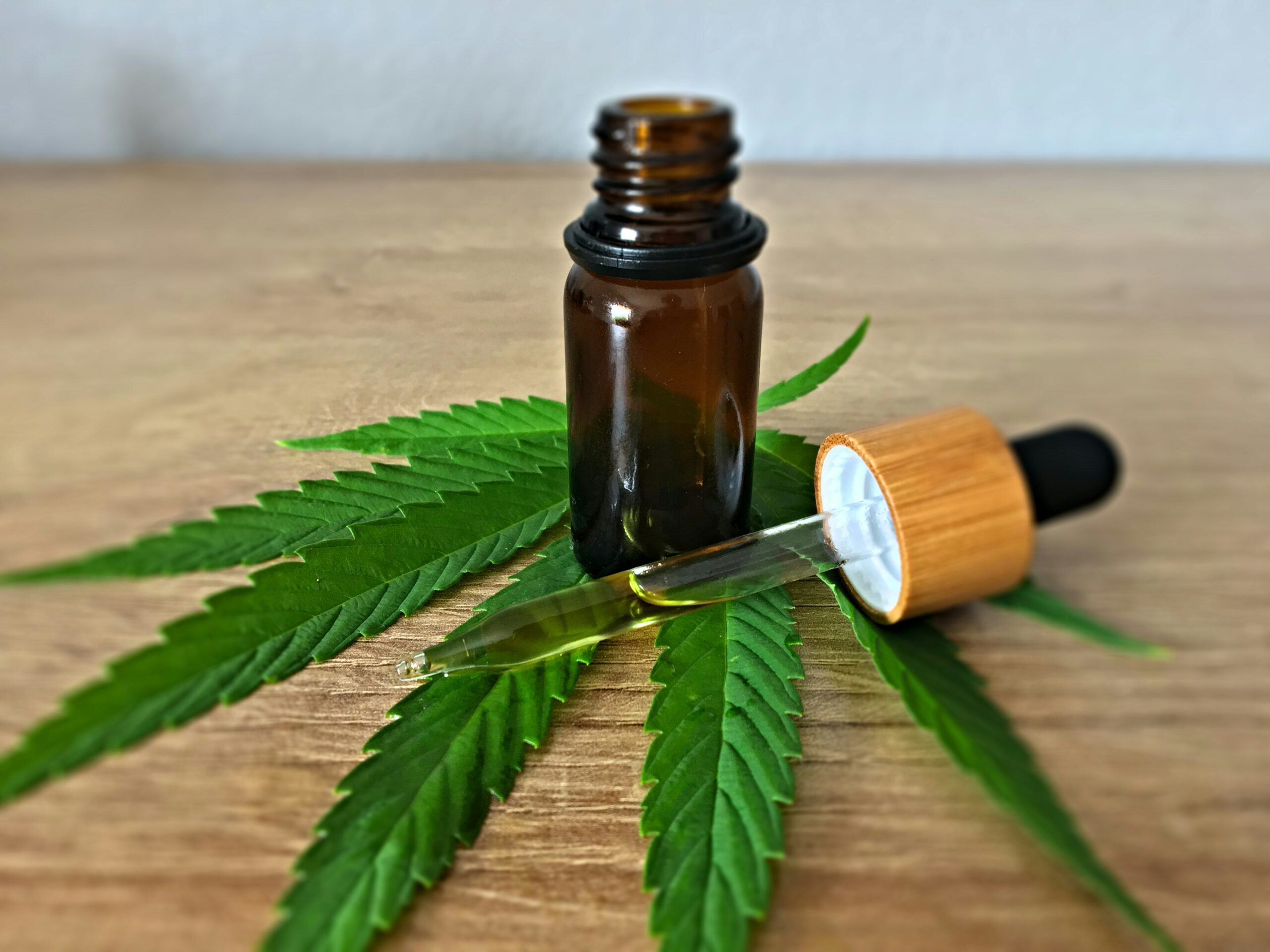 A dropper bottle of CBD oil with cannabis leaves on a wooden surface, representing cannabis delivery and weed delivery in Montreal.