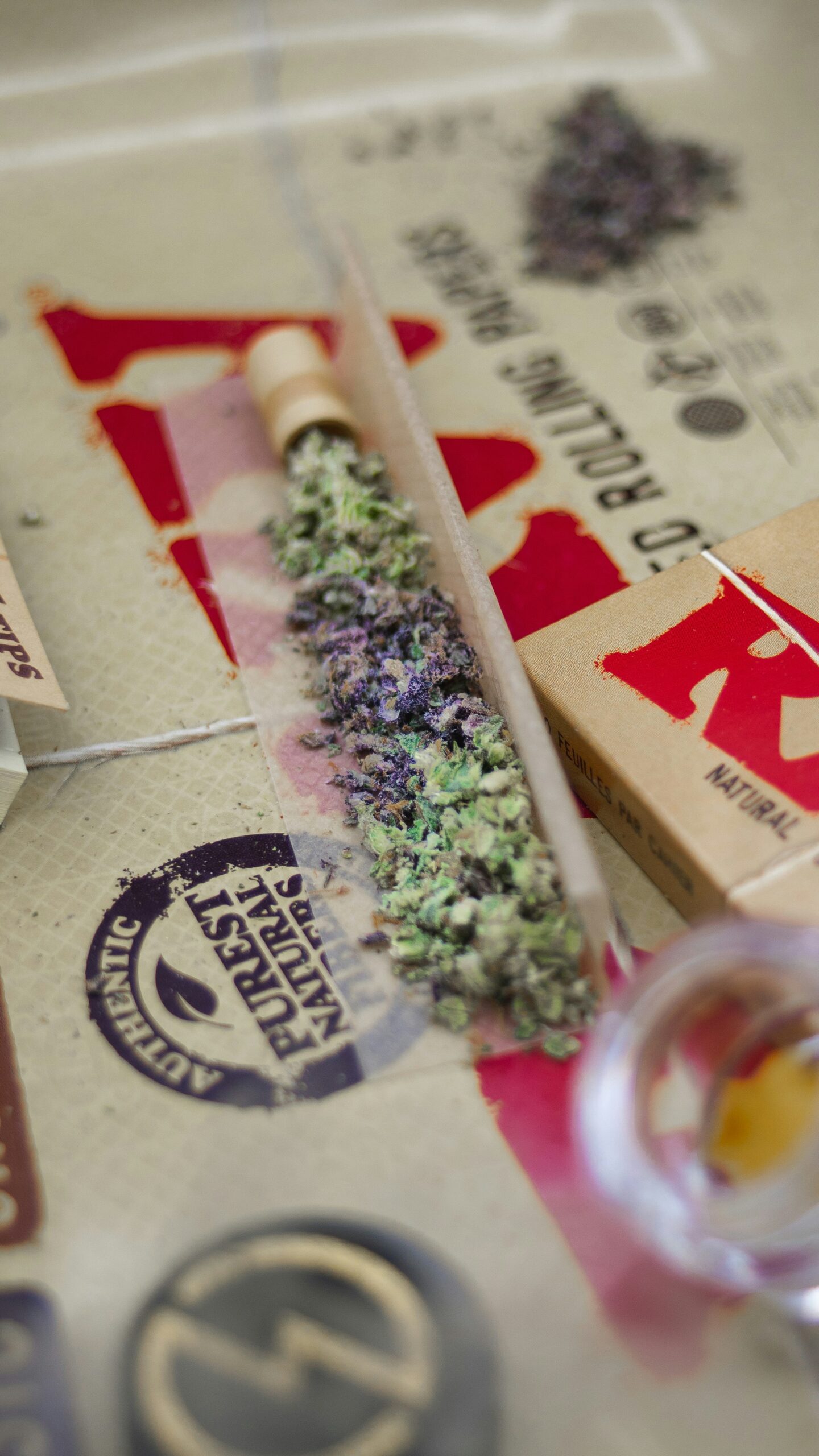 Close-up of rolling papers, cannabis, and a pre-rolled joint after a weed delivery.