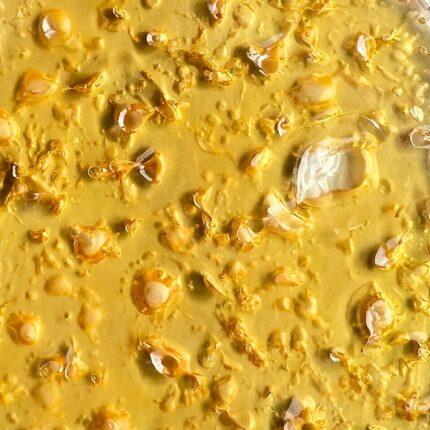 A vibrant close-up of Lemon Haze shatter, displaying its bright golden color and translucent quality.