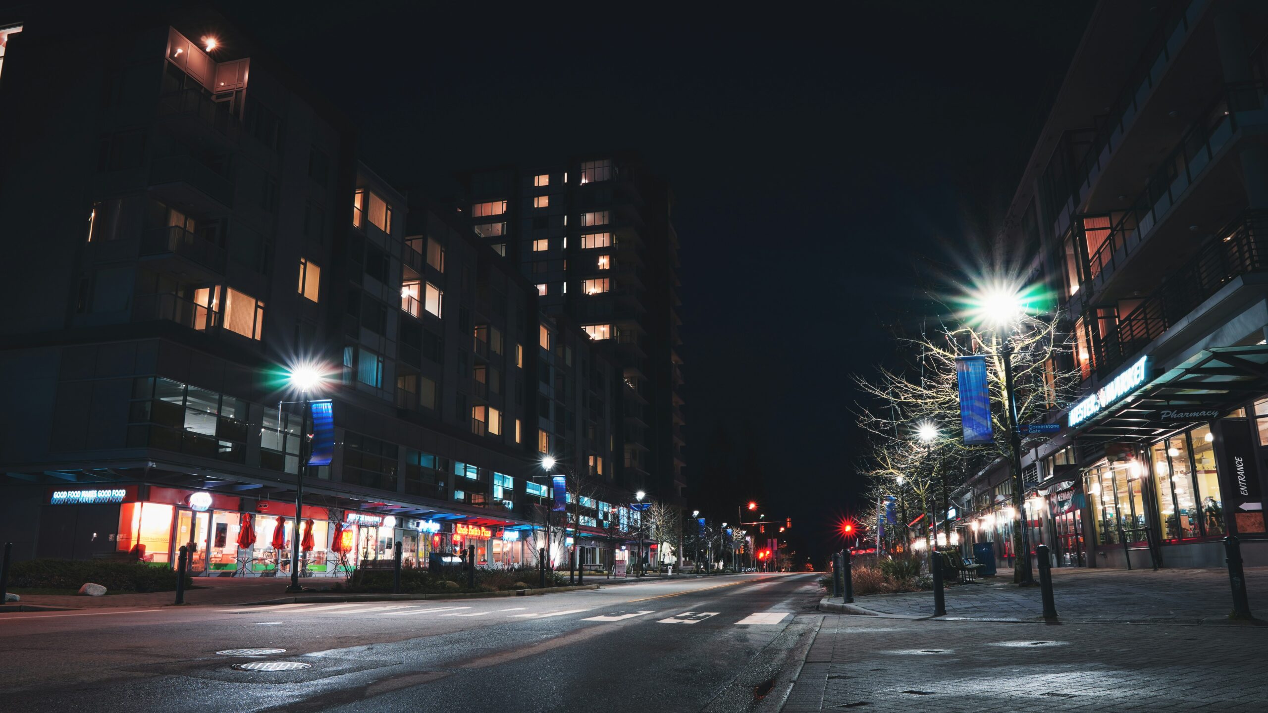 A quiet street in Burnaby at night with lit buildings and storefronts.
