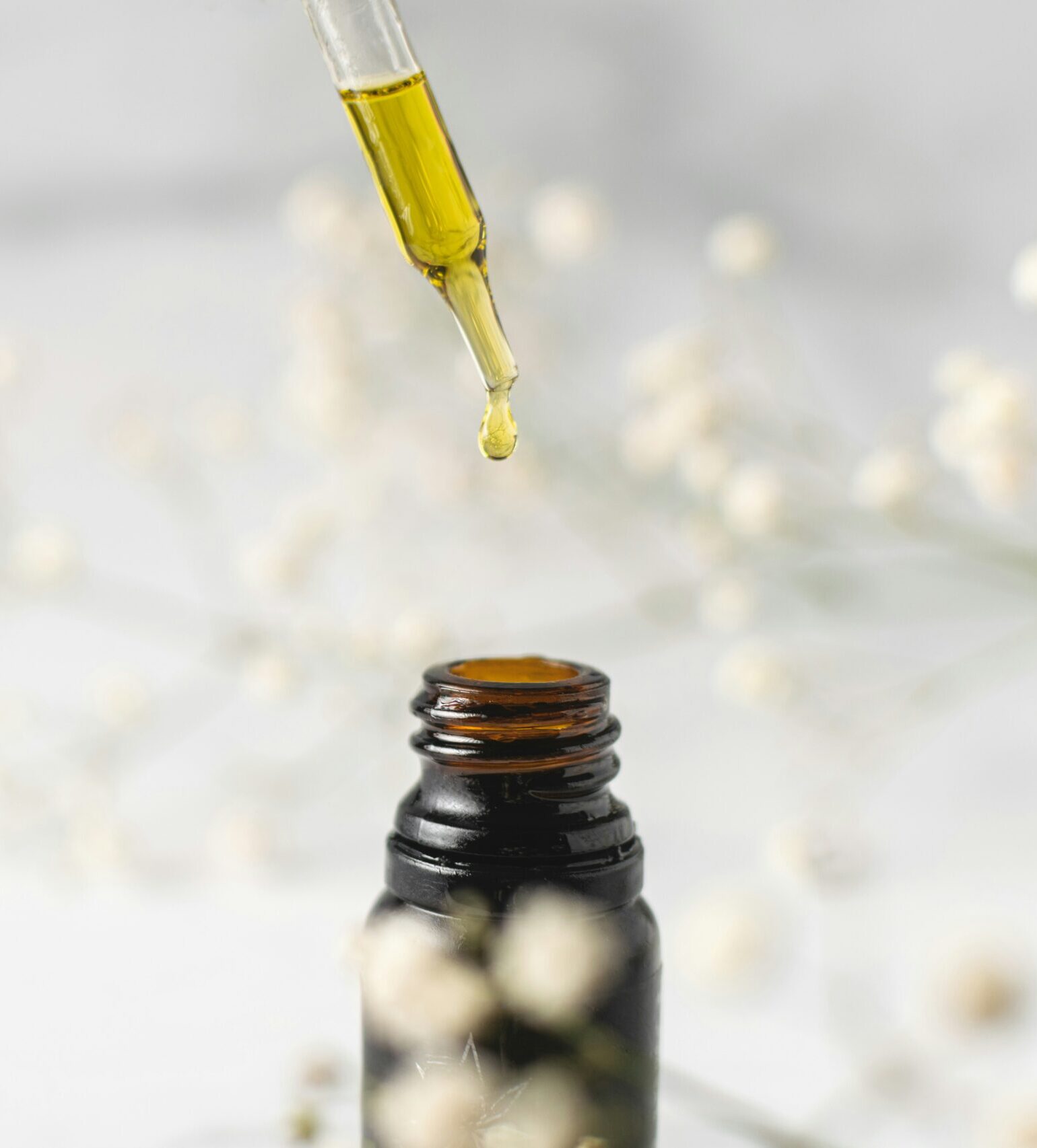 A dropper with cannabis oil above a small bottle.