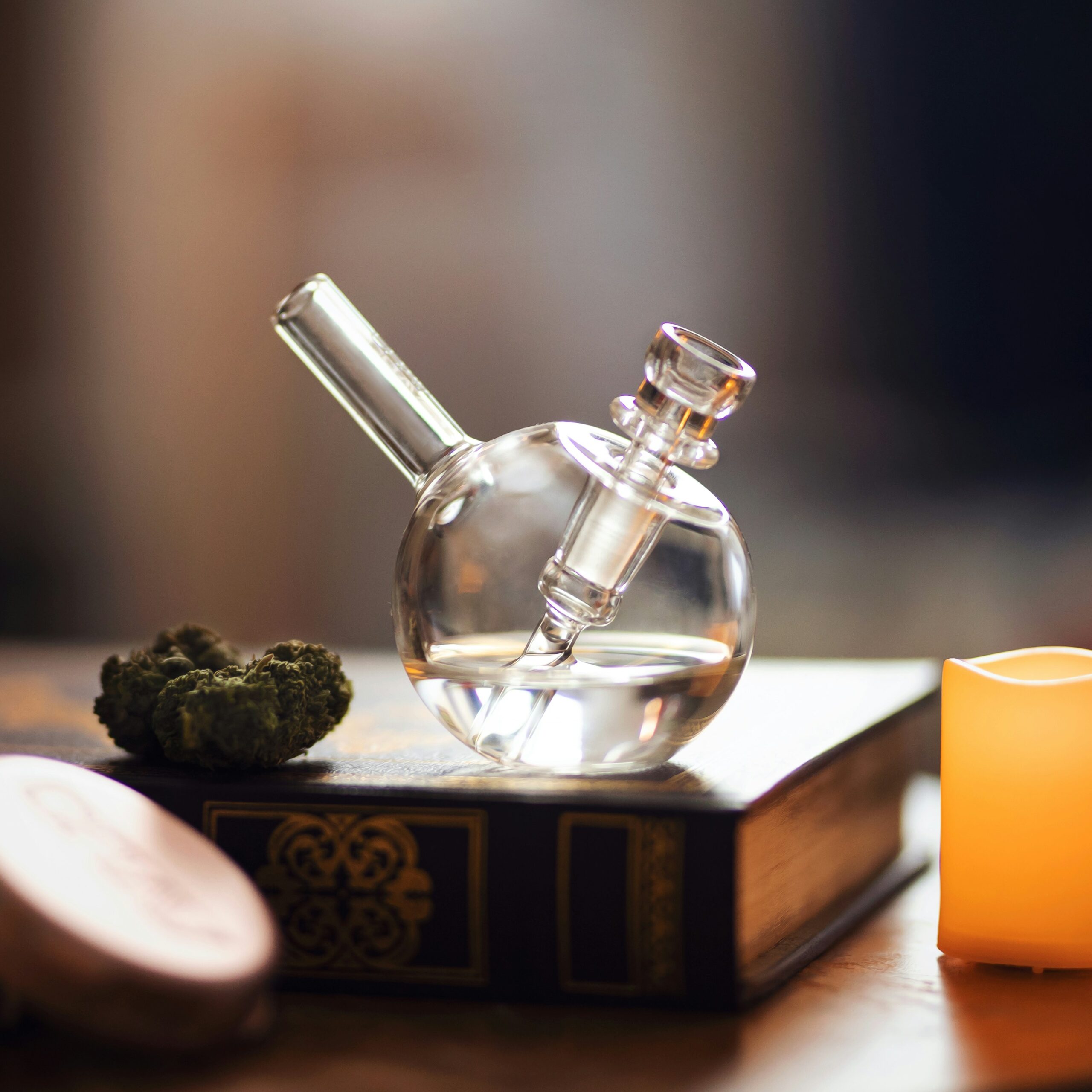 Weed delivery Edmonton: Glass pipe with cannabis on a wooden book