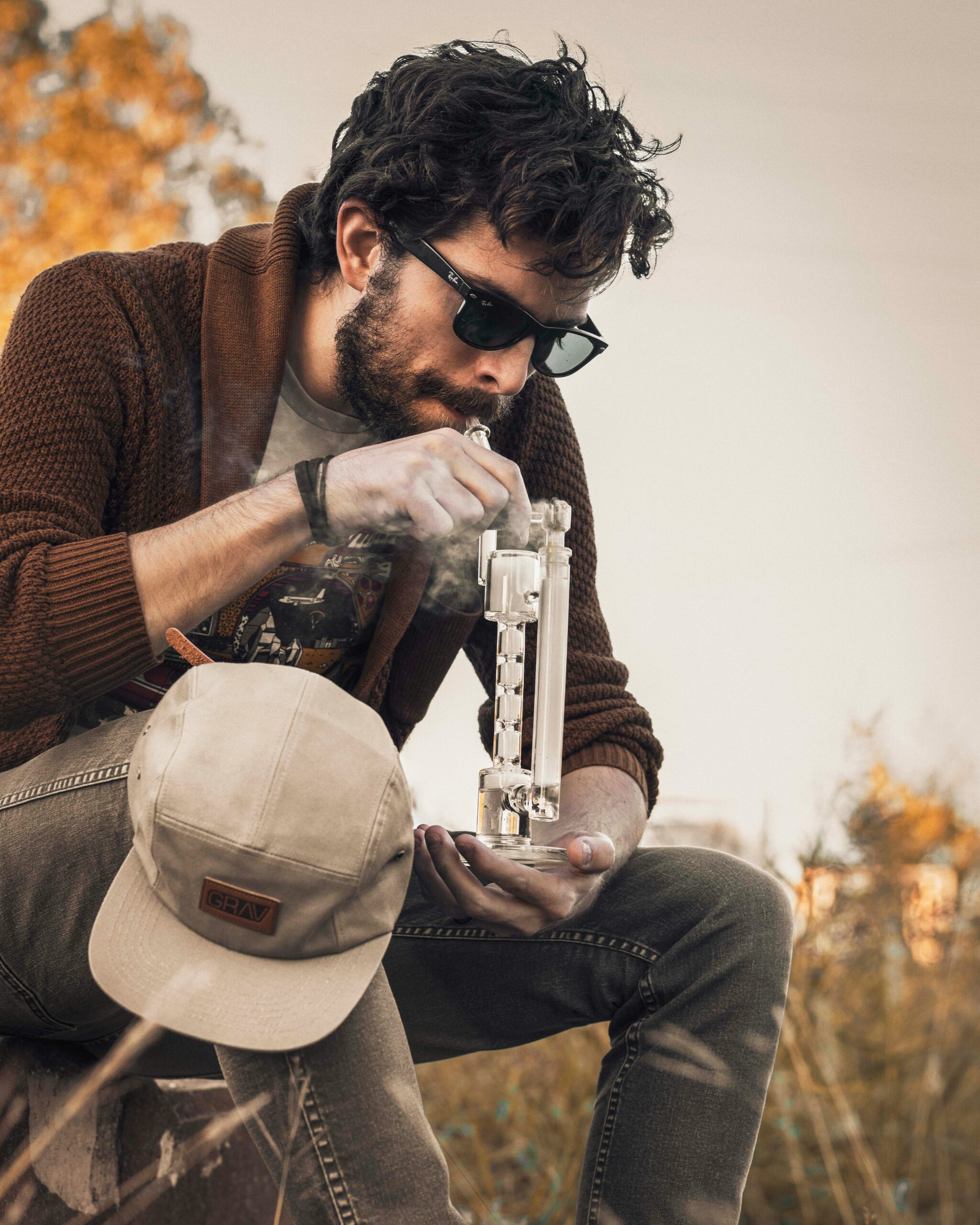 Man using a glass bong outdoors related to weed delivery Victoria