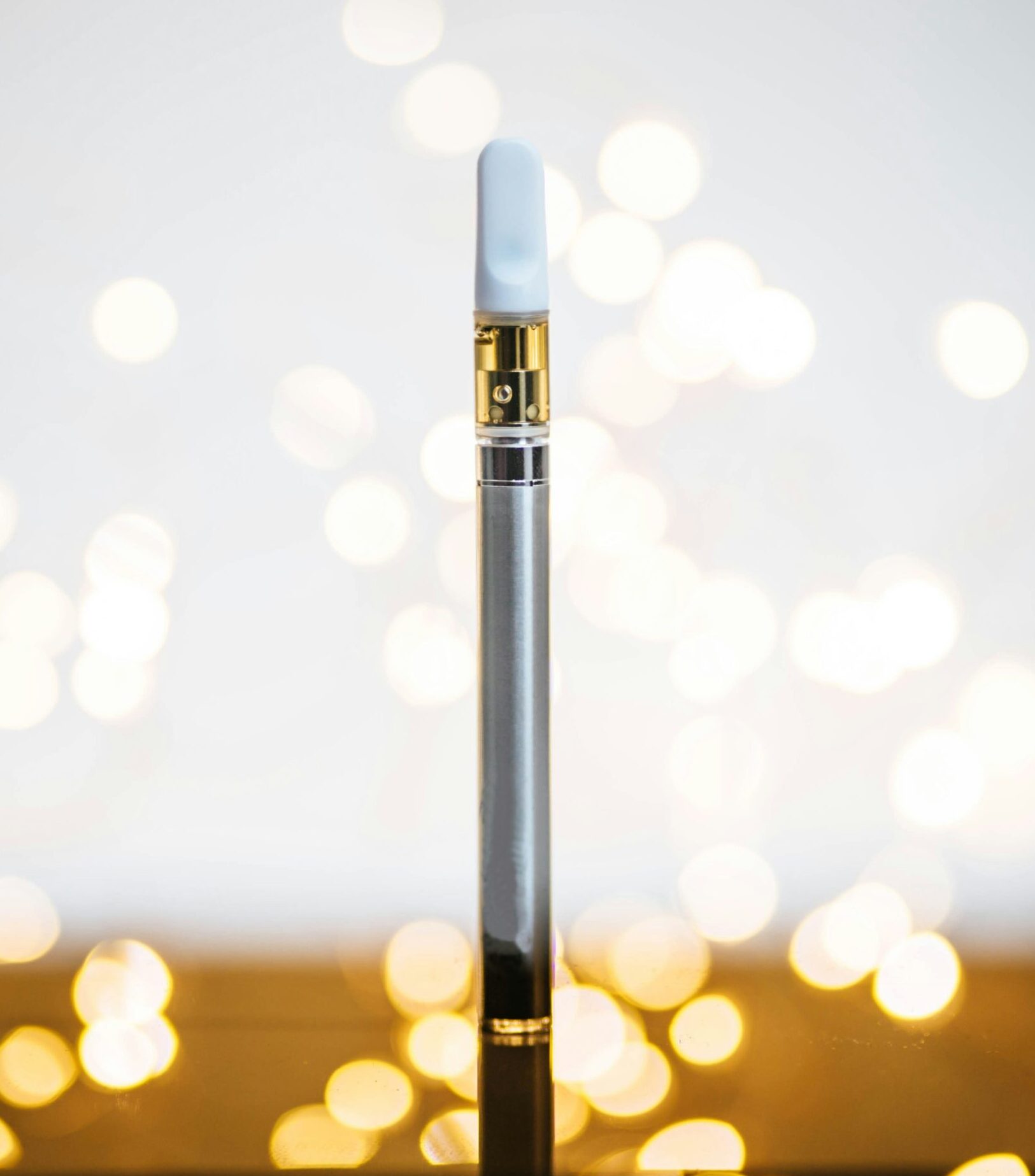 A sleek cannabis vape pen with bokeh lights in the background.