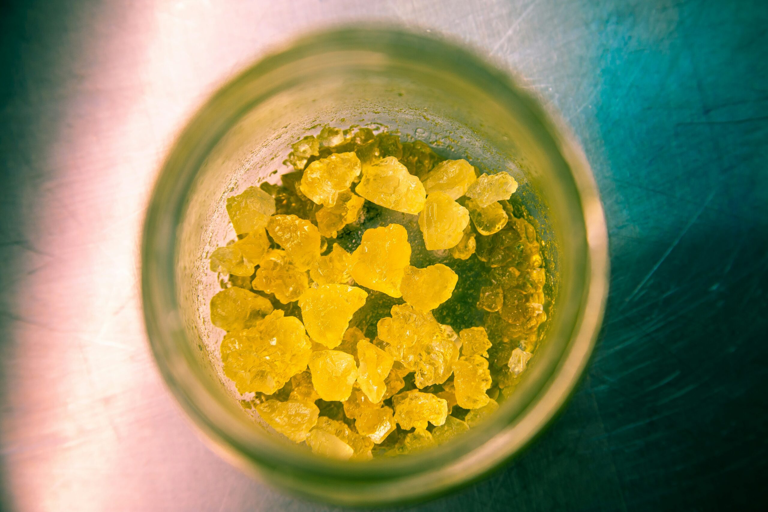 Weed delivery Winnipeg: Close-up view of yellow cannabis concentrate crystals in a glass jar.
