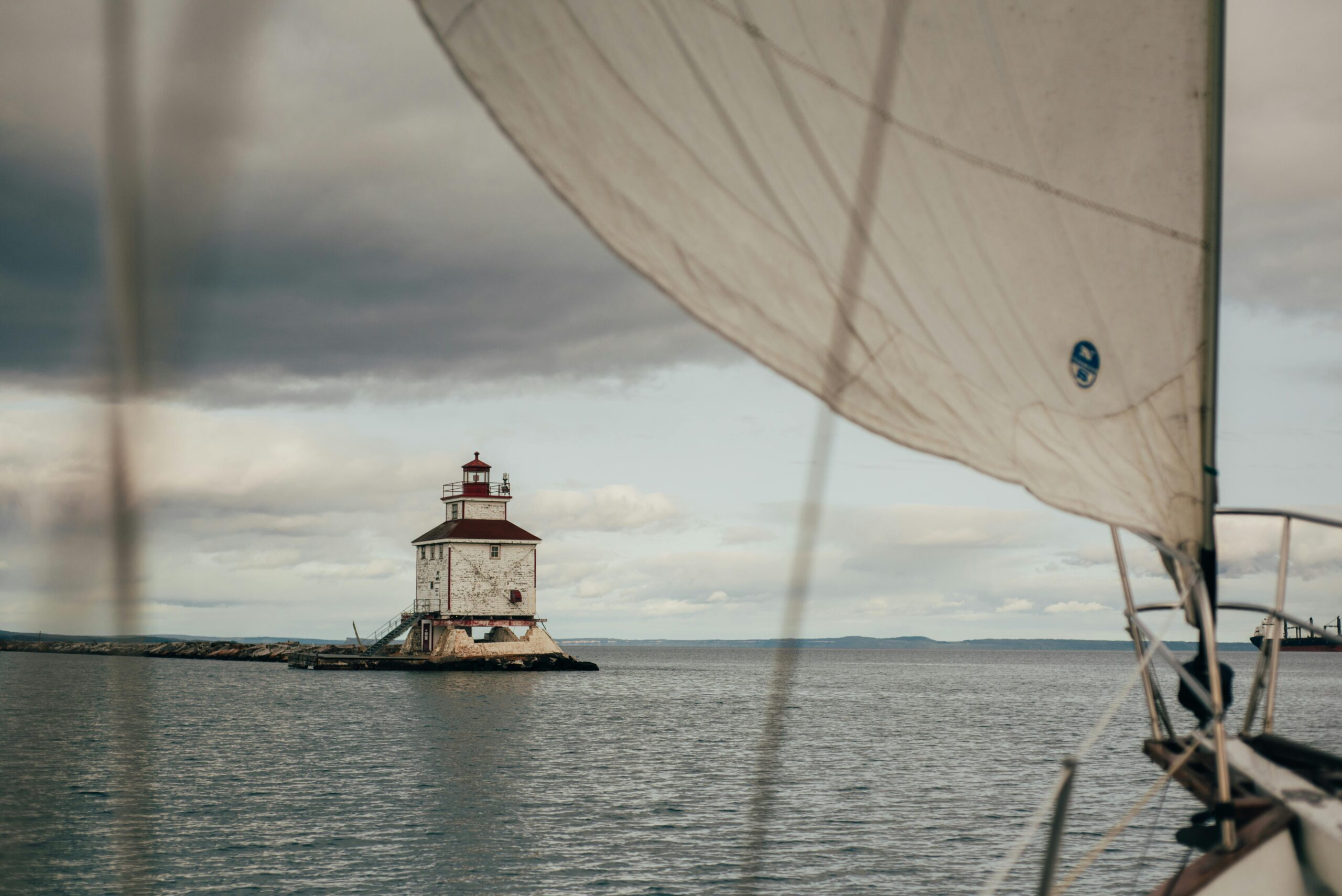 Lighthouse on Lake Superior in Thunder Bay with a sailboat in the foreground, representing weed delivery and cannabis weed services.