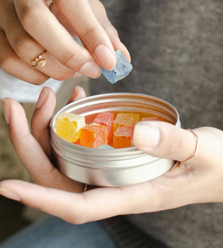 Person holding a tin of colorful cannabis edibles