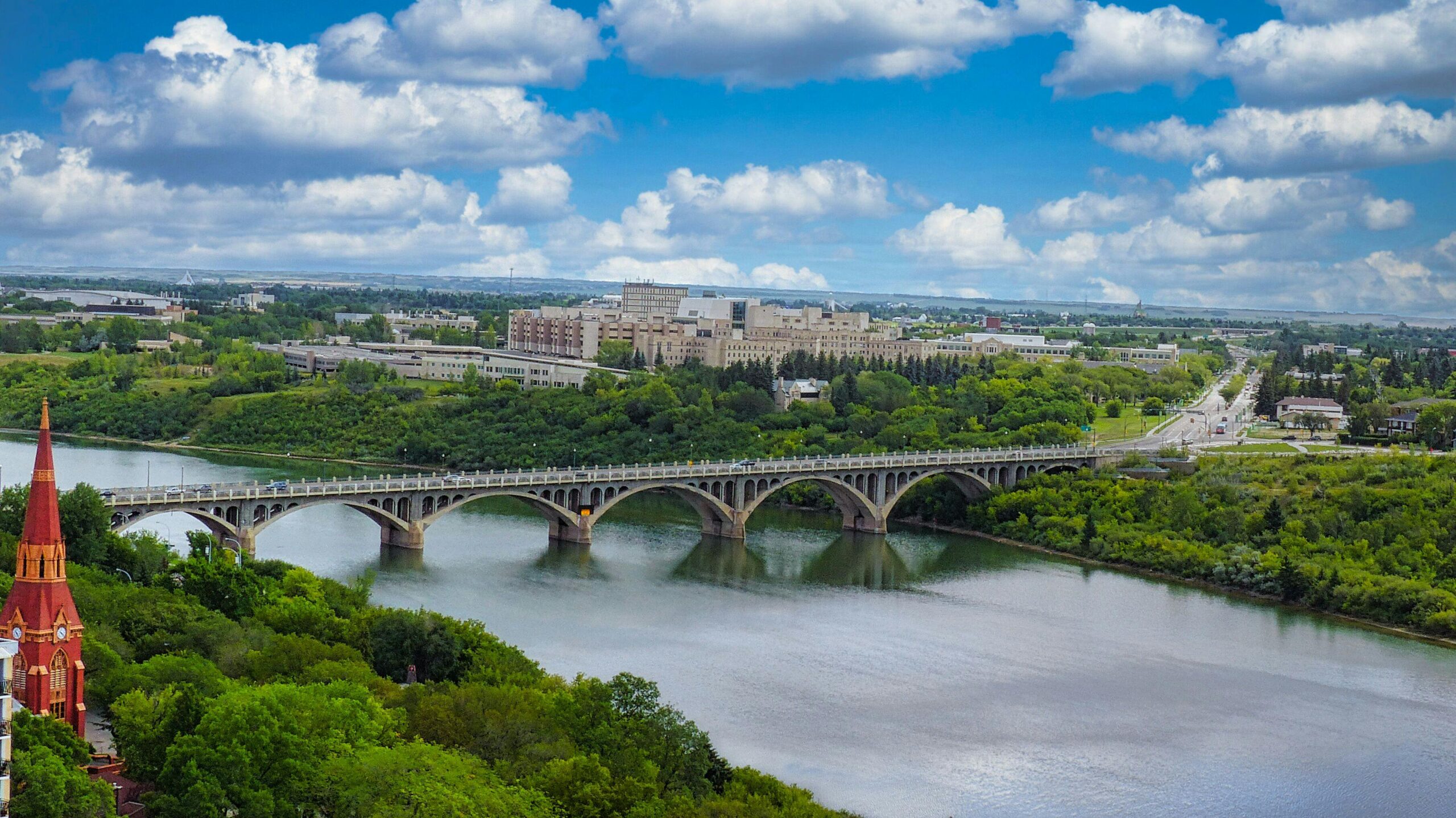Scenic view of Saskatoon city with a bridge and lush greenery, home to reliable weed delivery