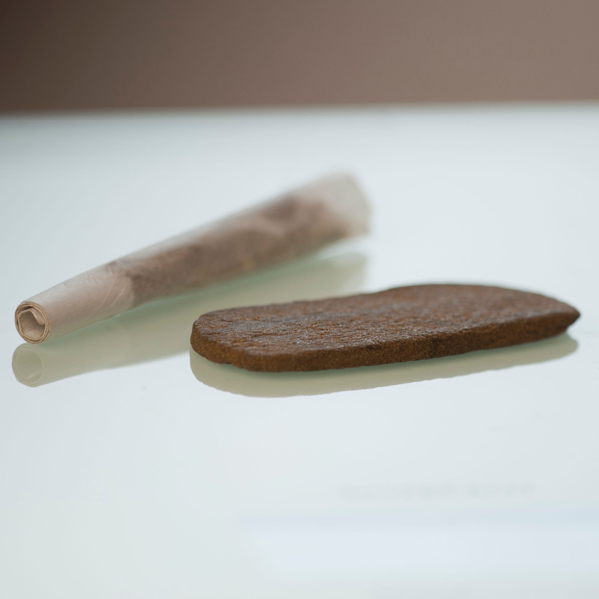 Moroccan Habibi Hash and a rolled joint on a reflective surface.