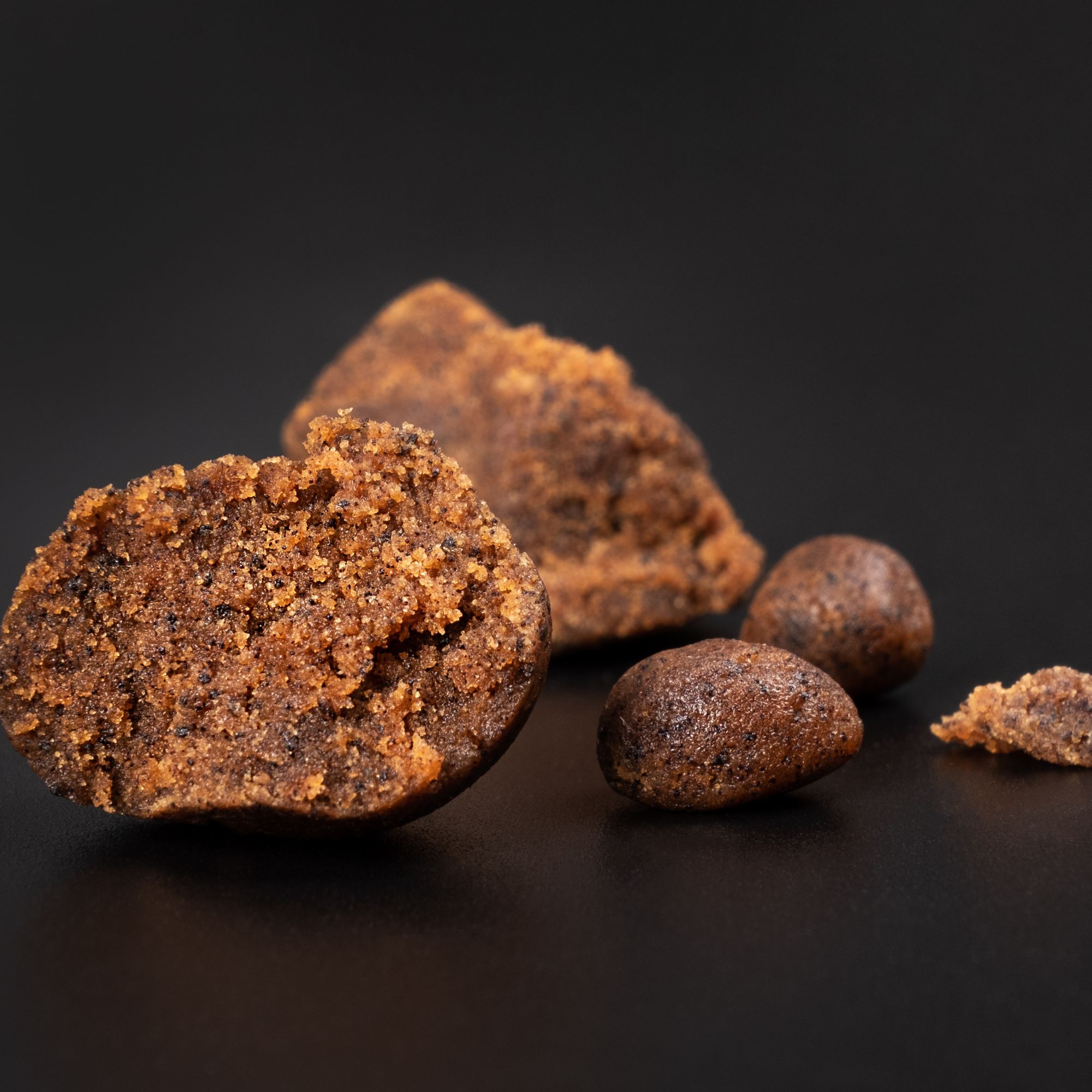 Crumbled pieces of Moroccan Habibi Hash on a black background.